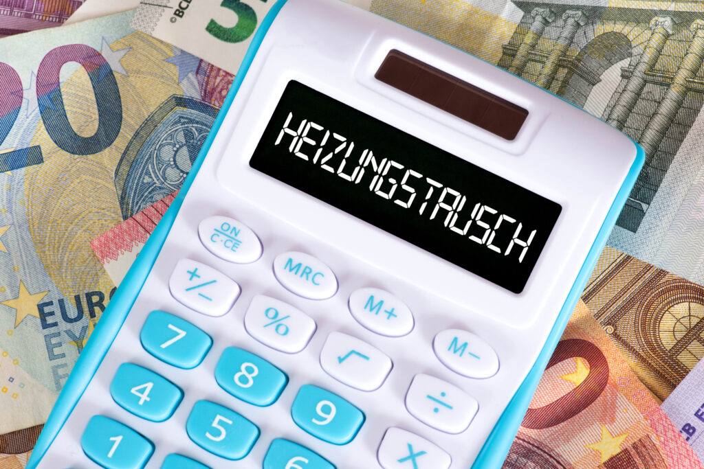 Euroscheine liegen unter einem Taschenrechner, der im Display „Heizungstausch“ stehen hat.